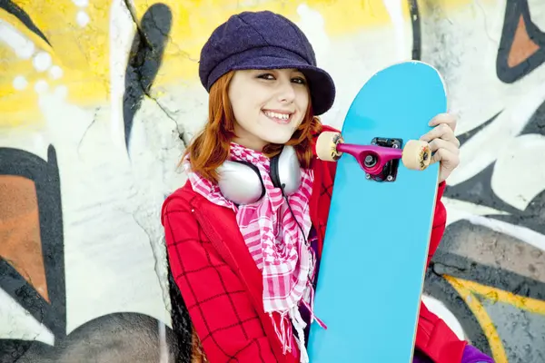 Closeup portrait of a happy young girl with skateboard and graff — Stock Photo, Image