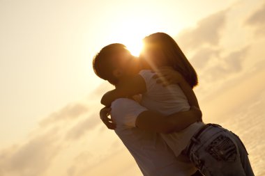 Couple kissing in sunrise at the beach. clipart