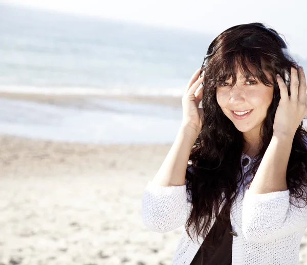 Красивая молодая женщина с наушниками на пляже — стоковое фото