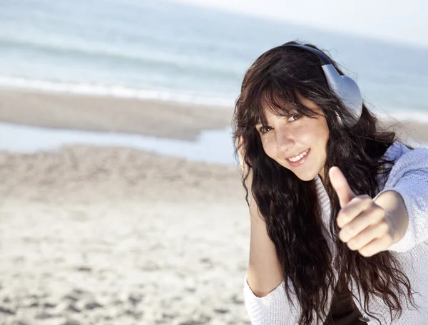 Mulher bonita com fone de ouvido na praia — Fotografia de Stock