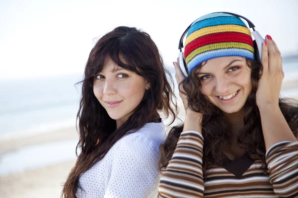 Chicas lindas en la playa. Uno de ellos con auriculares . — Foto de Stock