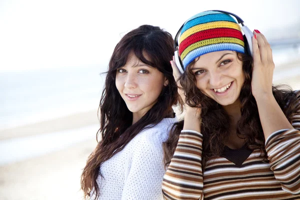 Chicas lindas en la playa. Uno de ellos con auriculares . — Foto de Stock
