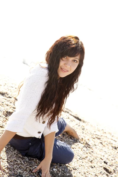 Sahilde oturmuş olan genç ve güzel kadın — Stok fotoğraf