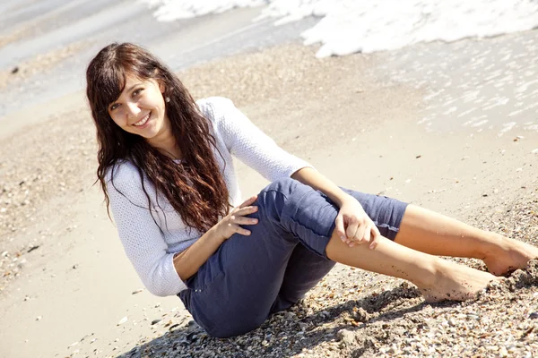 Hezká mladá žena s sedí na pláži — Stock fotografie