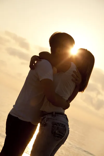 Casal beijando ao nascer do sol na praia . — Fotografia de Stock