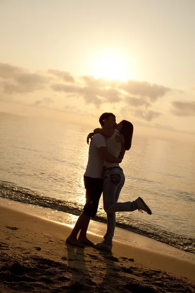 Paar zoenen in zonsopgang op het strand. — Stockfoto