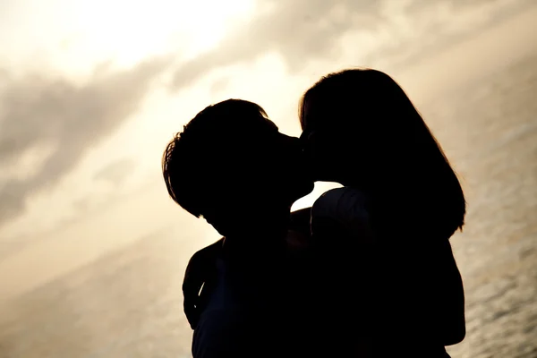 Pareja besándose al amanecer en la playa . —  Fotos de Stock