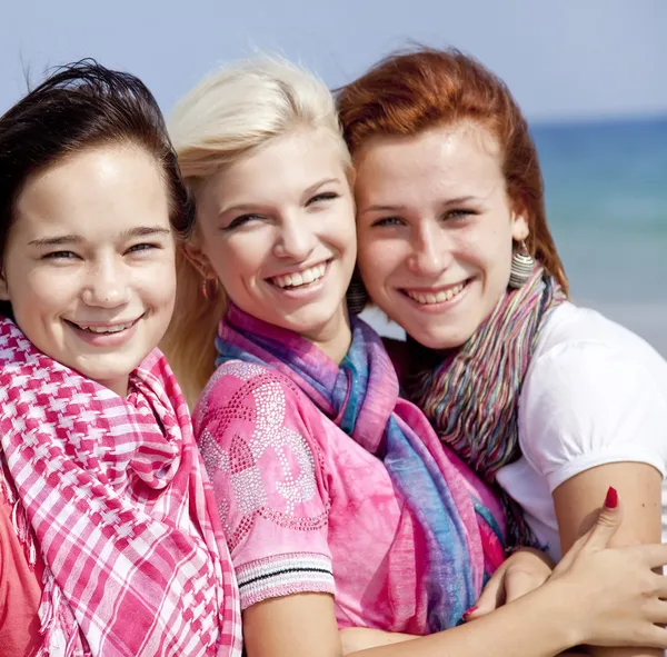 Drie knuffelen meisjes op het strand. — Stockfoto