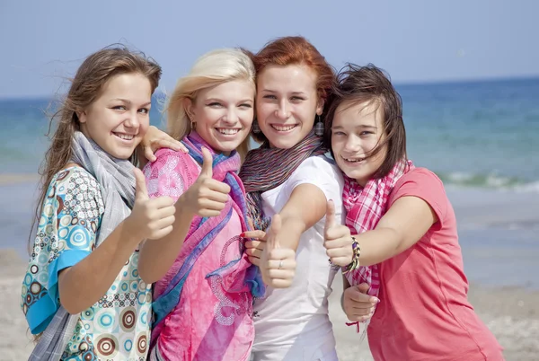Four hugging girlfriends at the beach show OK symbol. — Stock Photo, Image