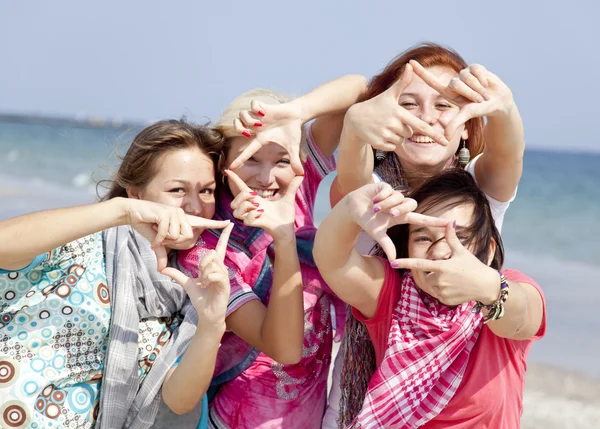 Vier Freundinnen am Strand zeigen Handrahmen. — Stockfoto