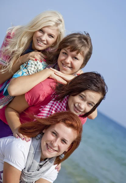Vier umarmende Freundinnen am Strand. — Stockfoto