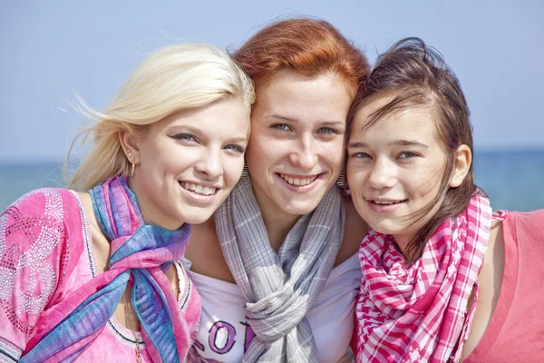 Drie knuffelen meisjes op het strand. — Stockfoto