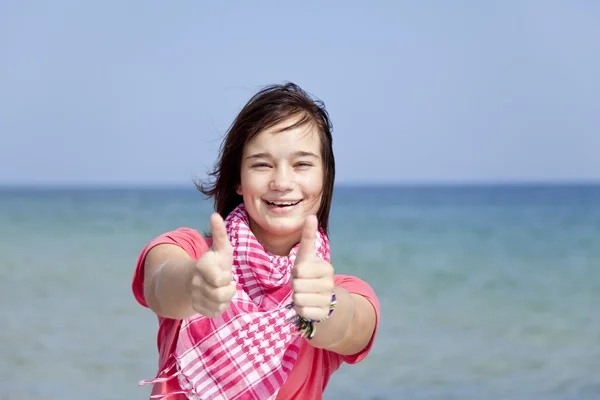 Junge brünette Mädchen am Strand zeigen ok Symbol. — Stockfoto