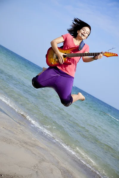 Młoda dziewczyna brunet z gitarą na plaży. — Zdjęcie stockowe