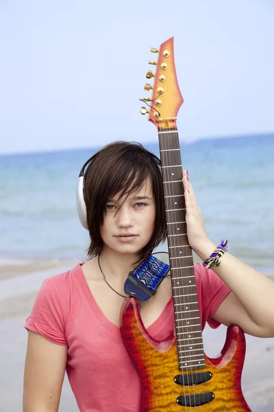 耳机和吉他在海滩上的年轻 brunet 女孩. — 图库照片