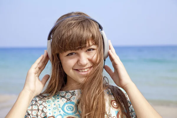 Giovane ragazza bruna con le cuffie sulla spiaggia . — Foto Stock