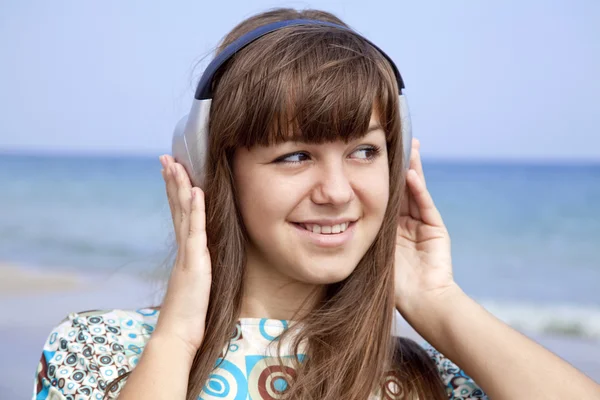 Fiatal brunet lány a strandon fejhallgató. — Stock Fotó