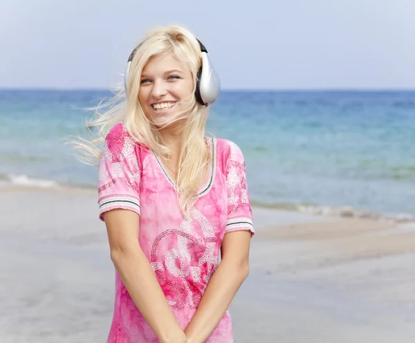 Fiatal szőke lány a strandon fejhallgató. — Stock Fotó