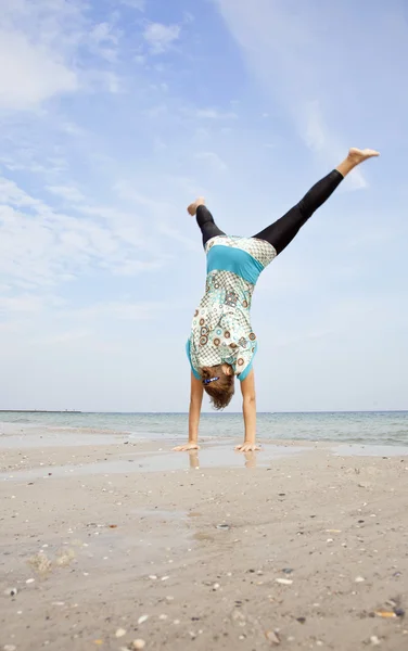 Fiatal lány egy akrobatikus Térkép a strandon. — Stock Fotó