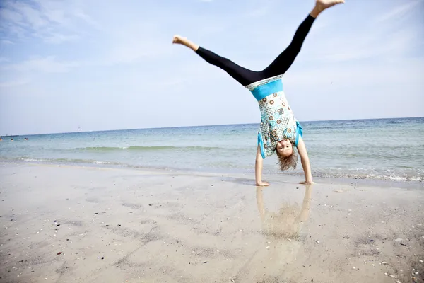 Junges Mädchen zeigt eine Akrobatik am Strand. — Stockfoto