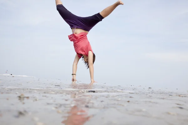 Ung flicka visar en akrobatisk på stranden. — Stockfoto