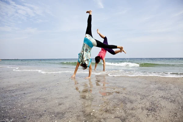 Menina jovem mostrar um acrobático na praia . — Fotografia de Stock