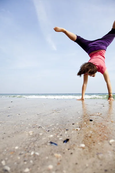 Молодая девушка показывает акробата на пляже . — стоковое фото