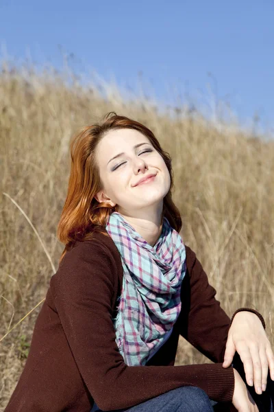 Portret van gelukkig roodharige meisje op herfst gras. — Stockfoto