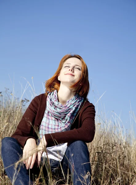 Portrait of happy red-haired girl on autumn grass. — Stock Photo, Image
