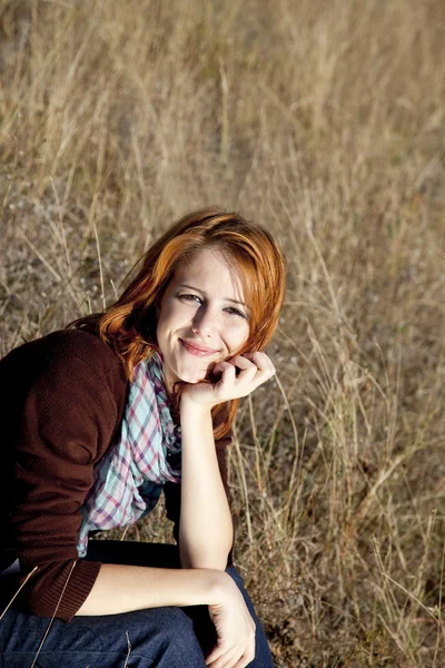 Portret van gelukkig roodharige meisje op herfst gras. — Stockfoto