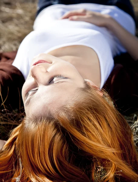 A vörös hajú lány portréja melyik lefekszik a földre. — Stock Fotó
