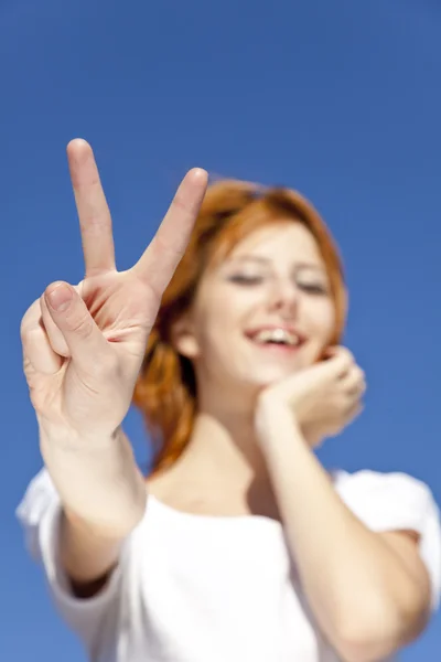 Portrait of red-haired girl in white which show hand V symbol. — Stock Photo, Image