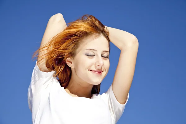 Portrait of red-haired girl in white on blue sky background. — Stock Photo, Image
