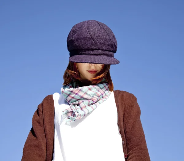 Porträtt av rödhårig tjej med halsduk och lila mössa på blå sk — Stockfoto