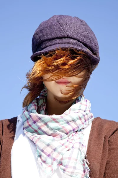Porträt eines rothaarigen Mädchens mit Schal und lila Mütze auf blauem Grund — Stockfoto