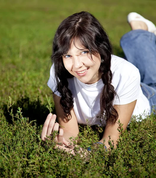 Portrait of beautiful brunette girl with blue eyes on green gras — Stock Photo, Image