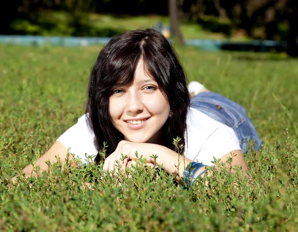 Portret van mooie brunette meisje met blauwe ogen op groen gras — Stockfoto