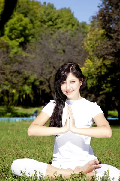 Beautiful young brunet yoga girl on green grass in park. — Stock Photo, Image