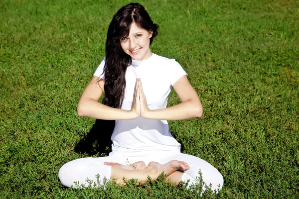 Beautiful young brunet yoga girl on green grass in park. — Stock Photo, Image