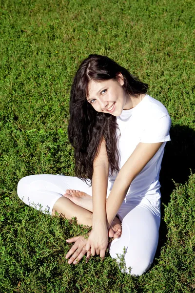 Vackra unga brunet yoga flicka på grönt gräs i parken. — Stockfoto