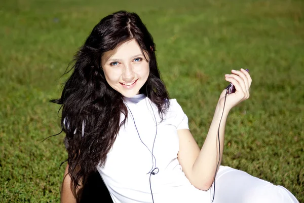 Muito jovem morena menina ouvir música na grama verde no — Fotografia de Stock