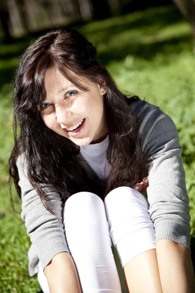 Portrét krásná brunetka s modrýma očima na zelené gras — Stock fotografie