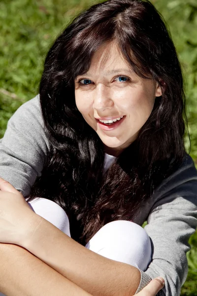 Portret pięknej dziewczyny brunetka o niebieskich oczach na zielony gras — Zdjęcie stockowe