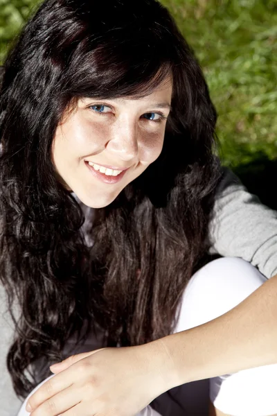 Portrét krásná brunetka s modrýma očima na zelené gras — Stock fotografie