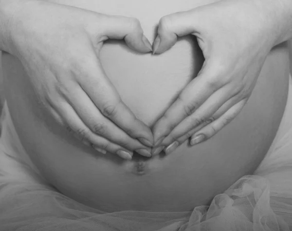 Έγκυος κοιλιά με τα χέρια σε μια καρδιά — Φωτογραφία Αρχείου