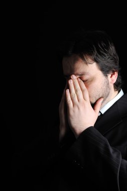 koyu arka plan üzerinde oturan yetişkin işadamı ciddi düşünme