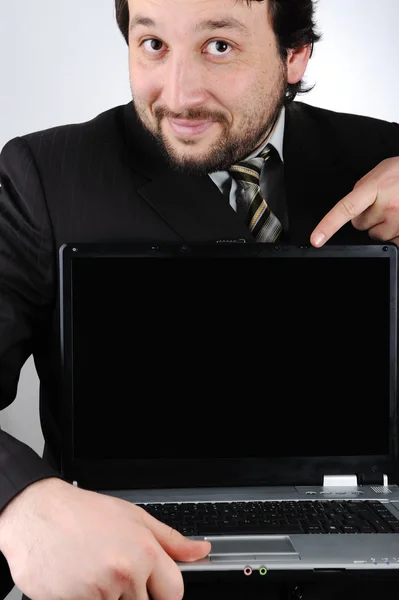 Χαμογελαστός νεαρός επιχειρηματίας κρατώντας lap-top με την κενή οθόνη και δείχνει την Πέμ — Φωτογραφία Αρχείου