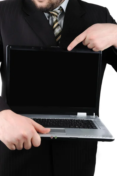 Smiling young businessman holding laptop with blank screen and showing thu — Stock Photo, Image