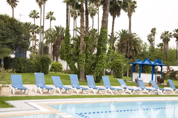 Zwembad met chaise lounge en parasol in tropische resort — Stockfoto