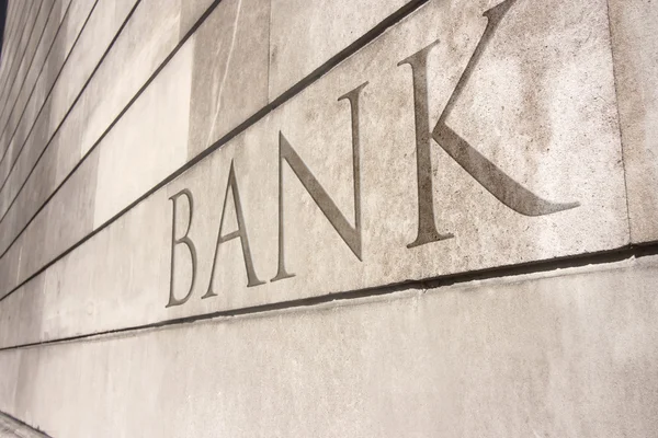 Écriture de banque gravée sur un mur de pierre — Photo